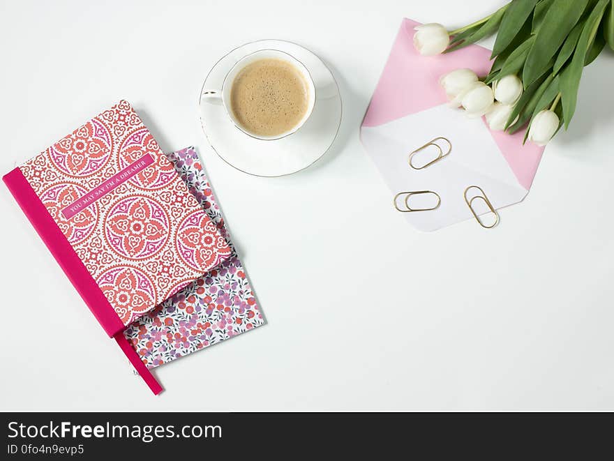 Brown Latte in Ceramic Mug Near Pink and White Floral Textile and White Tulips