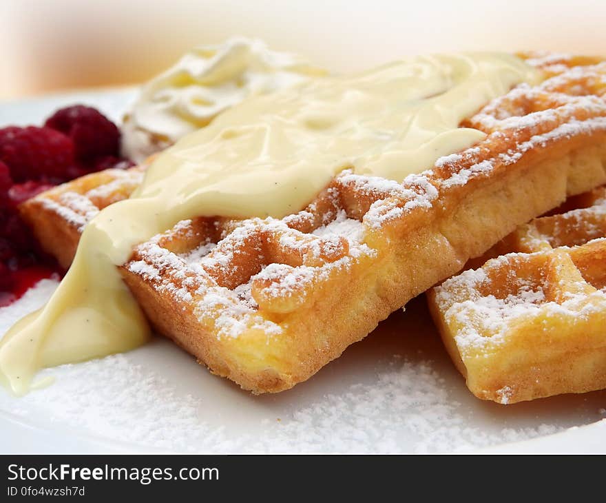 Freshly made waffles with vanilla sauce and raspberries sprinkled with sugar. Freshly made waffles with vanilla sauce and raspberries sprinkled with sugar.