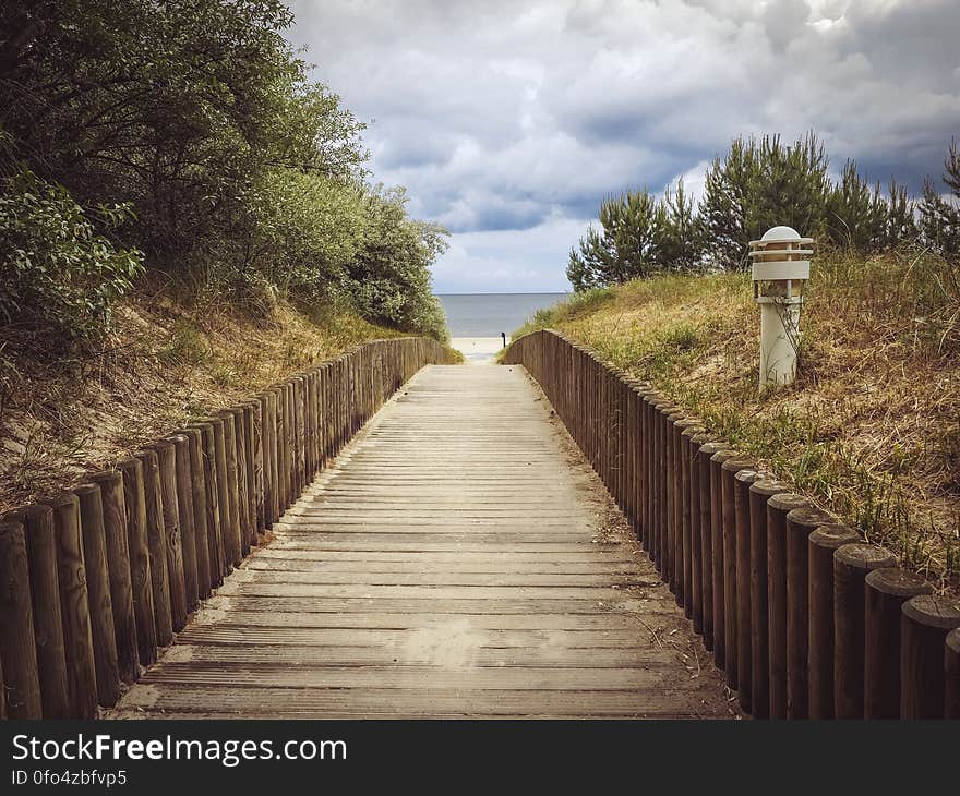 Straight wooden boardwalk leading to beach in distance.