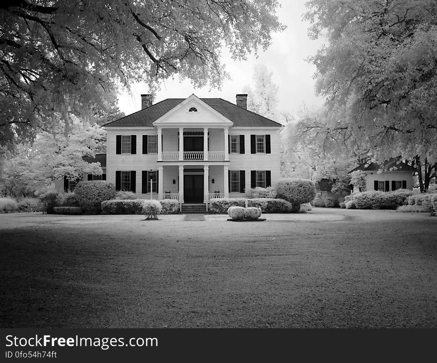 A black and white photo of a modern stylish house with a garden and a lawn. A black and white photo of a modern stylish house with a garden and a lawn.