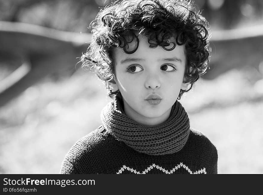 A black and white portrait of a child with curly hair.