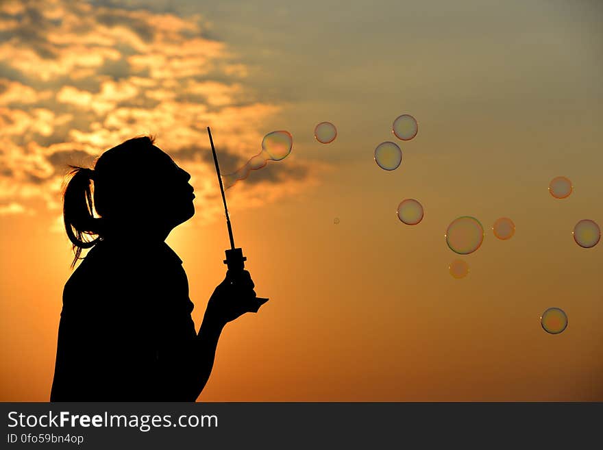 A girl blowing soap bubbles at sunset. A girl blowing soap bubbles at sunset.