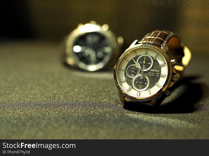 Two men's wristwatches on table surface. Two men's wristwatches on table surface.