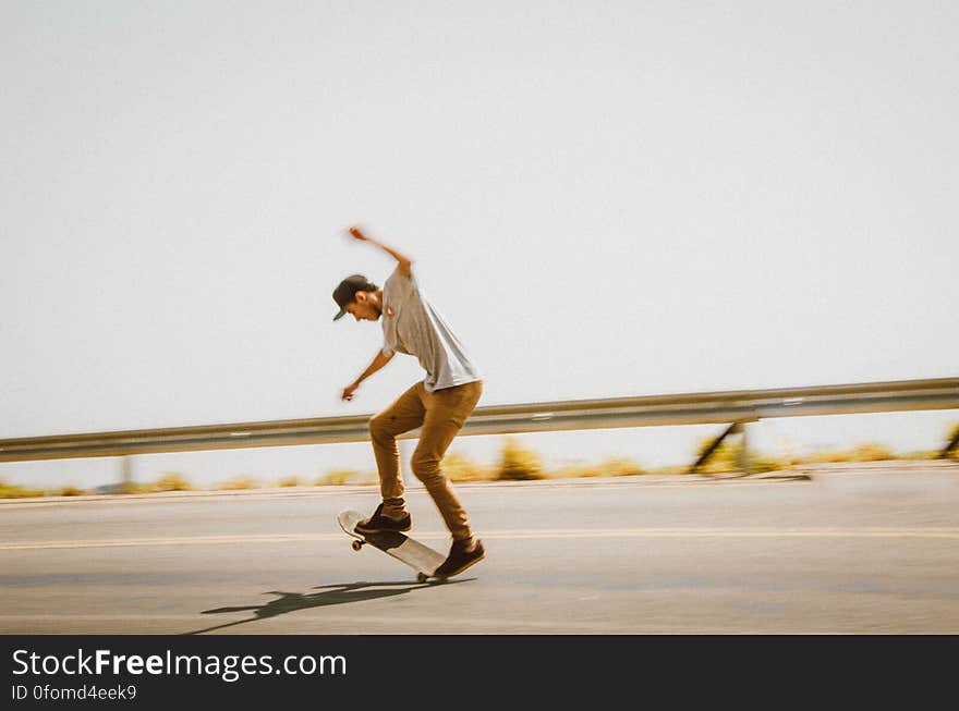 Young male skateboarder performing trick on asphalt road. Young male skateboarder performing trick on asphalt road.