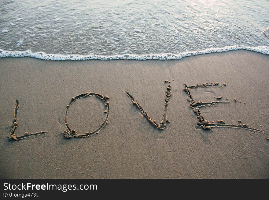 A close up of love sign on a sandy beach. A close up of love sign on a sandy beach.