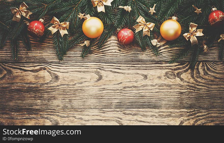 A Christmas background with baubles and conifer branches on wood background.