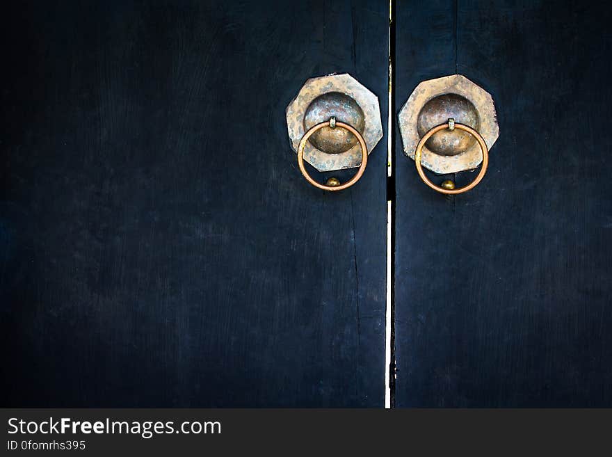 A pair of antique doors with brass pull handles.