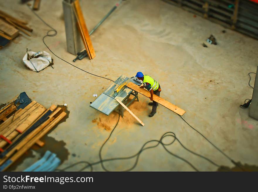 Person Cutting Wood on Table Saw during Daytime