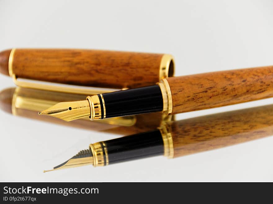 A close up of an elegant fountain pen mirroring on a glass surface.