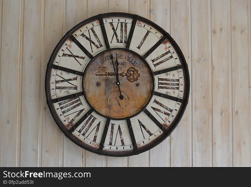 A close up of an old fashioned clock with Roman numerals hanging on a wall.