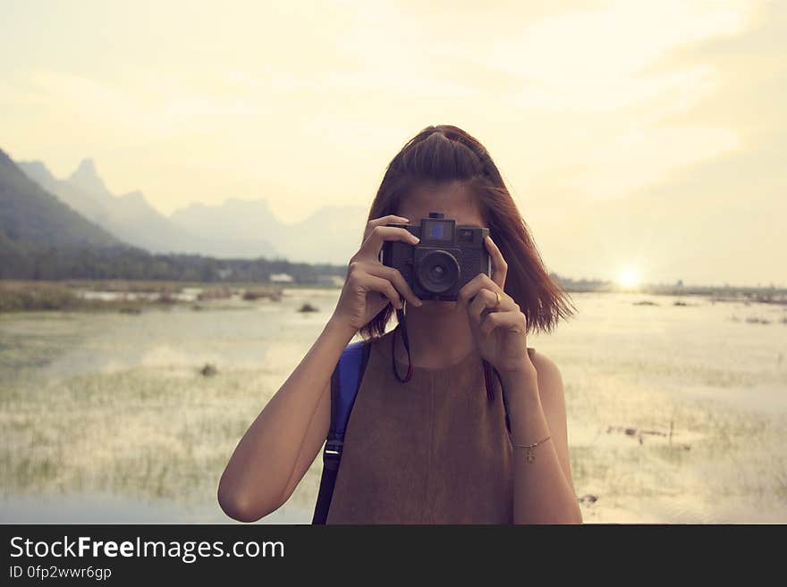 A portrait of a young woman taking photo outdoor.