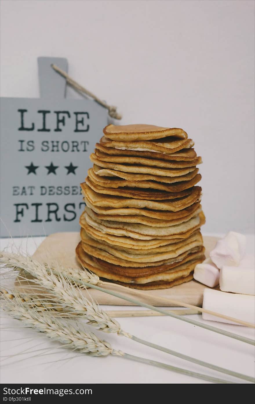 A stack of pancakes with marshmallows and ears of wheat.