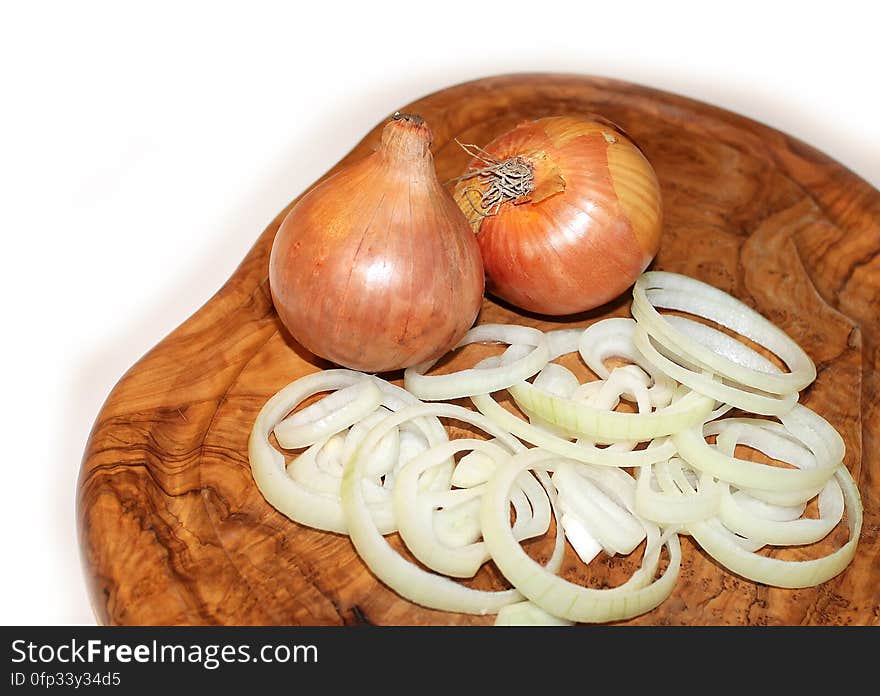 Whole yellow onions and onion rings on a cutting board. Whole yellow onions and onion rings on a cutting board.