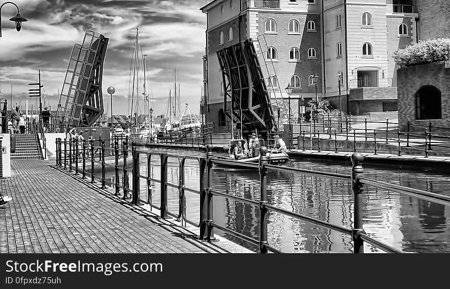 A black and white photo of a promenade and a canal in an old town. A black and white photo of a promenade and a canal in an old town.