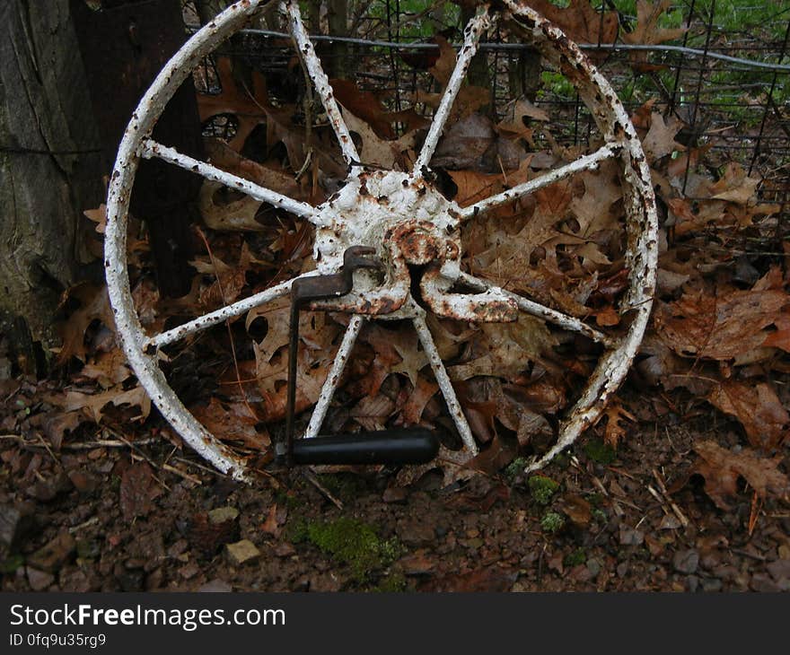 An old rusted wagon wheel against a fence. An old rusted wagon wheel against a fence