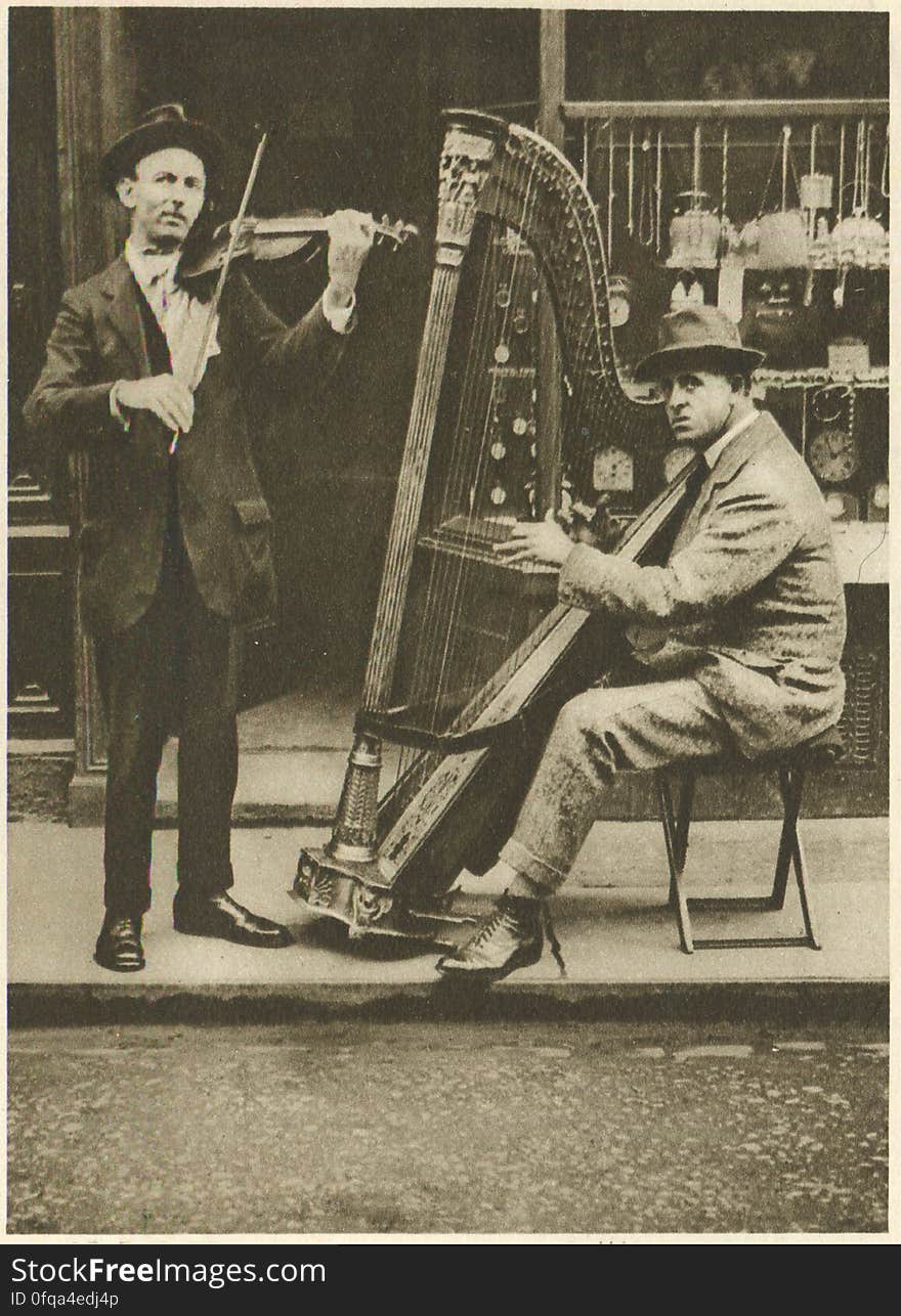 London, 1920s Photogravure by Donald Macleish from Wonderful London by St John Adcock, 1927. From the section entitled Some of the sights and sounds that liven London streets: Accompanied by a violin, he is the most melodious of all the street musicians - the strains of the itinerant harpist come through the din of traffic like distant echoes of Tara or Carleon.