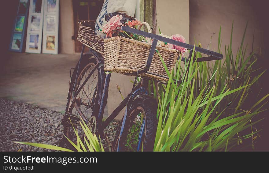 Vintage bicycle with baskets at front and rear popular for grocery and butchery deliveries propped up outside a shop.