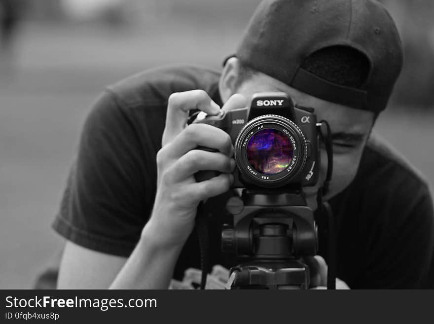 A black and white portrait of a young man taking photo.