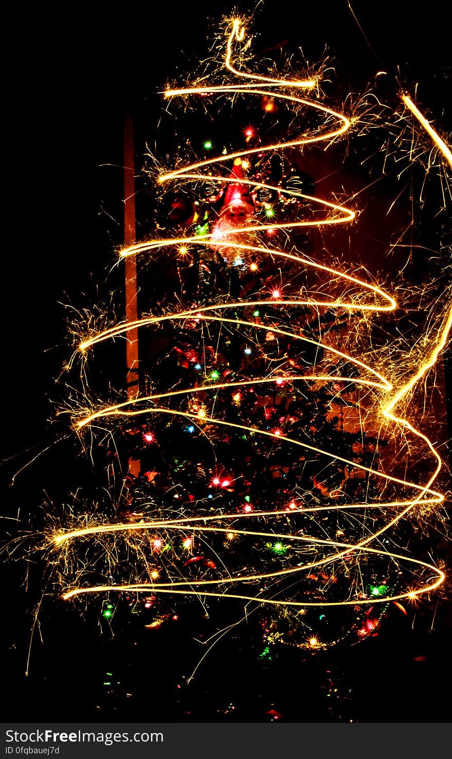 A long exposure of sparklers in front of a Christmas tree. A long exposure of sparklers in front of a Christmas tree.