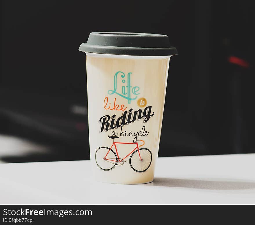 A paper coffee cup with lid and a bicycle illustration. A paper coffee cup with lid and a bicycle illustration.