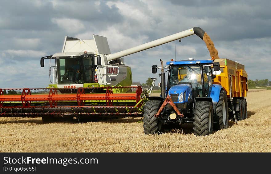 Blue Tractor Next to White Farm Vehicle at Daytime