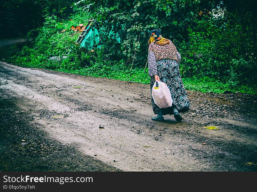 An elderly woman walking on a rural country road. An elderly woman walking on a rural country road.