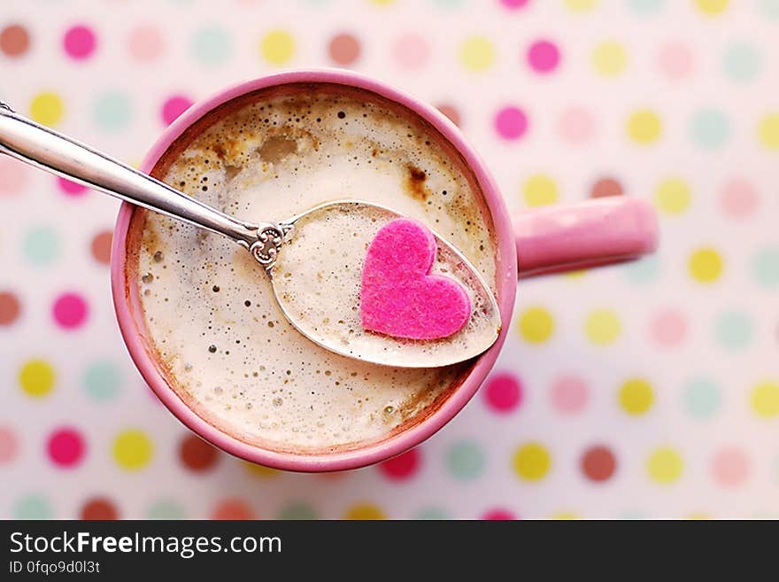 A hot drink in cup with a heart in the spoon. A hot drink in cup with a heart in the spoon.