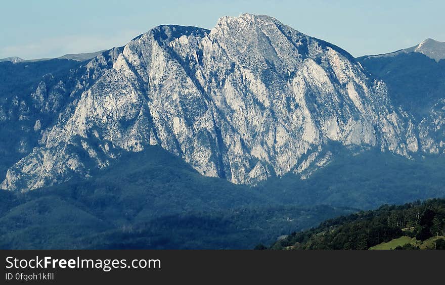 A view of a rocky mountain range and green forest.