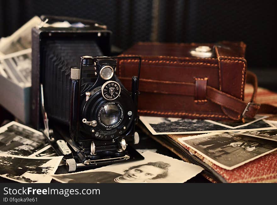 Vintage camera and case with photographs spread on table. Vintage camera and case with photographs spread on table.