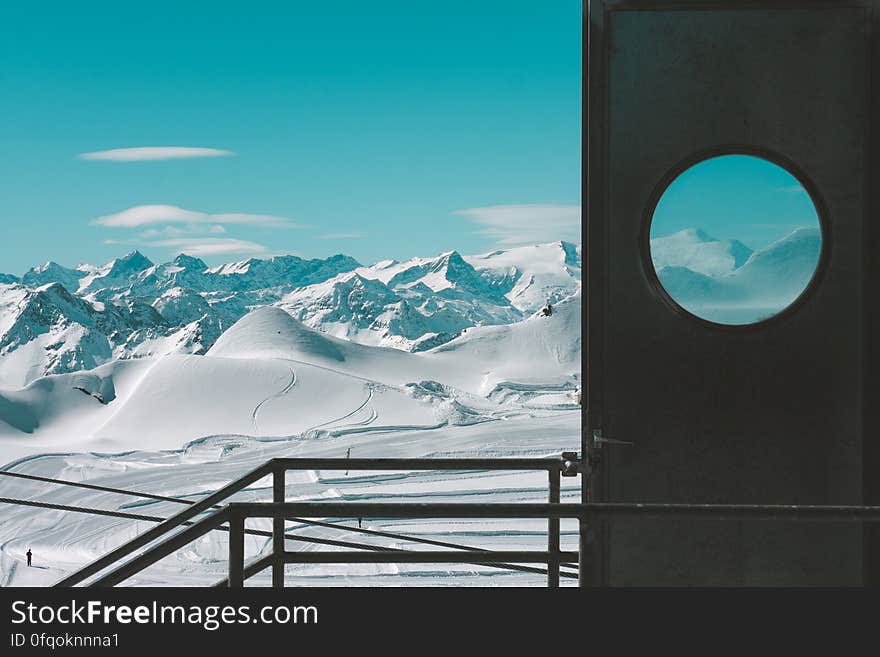 Frozen mountain landscape with deep snow observed from a view point with safety railings, background of pale blue sky. Frozen mountain landscape with deep snow observed from a view point with safety railings, background of pale blue sky.