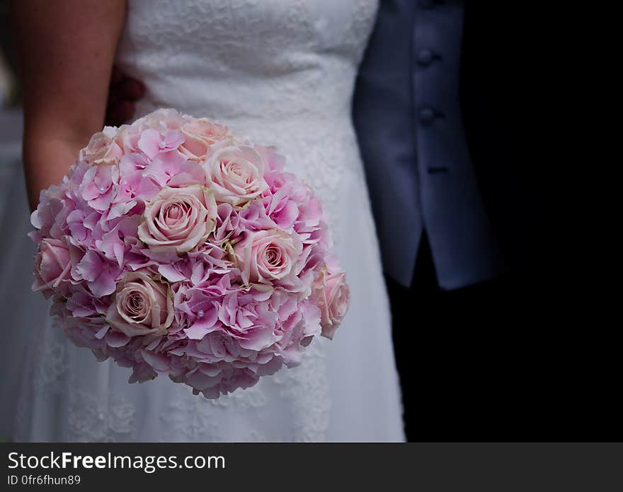 Woman in White Wedding Dress Holding a Bouquet of Flowers