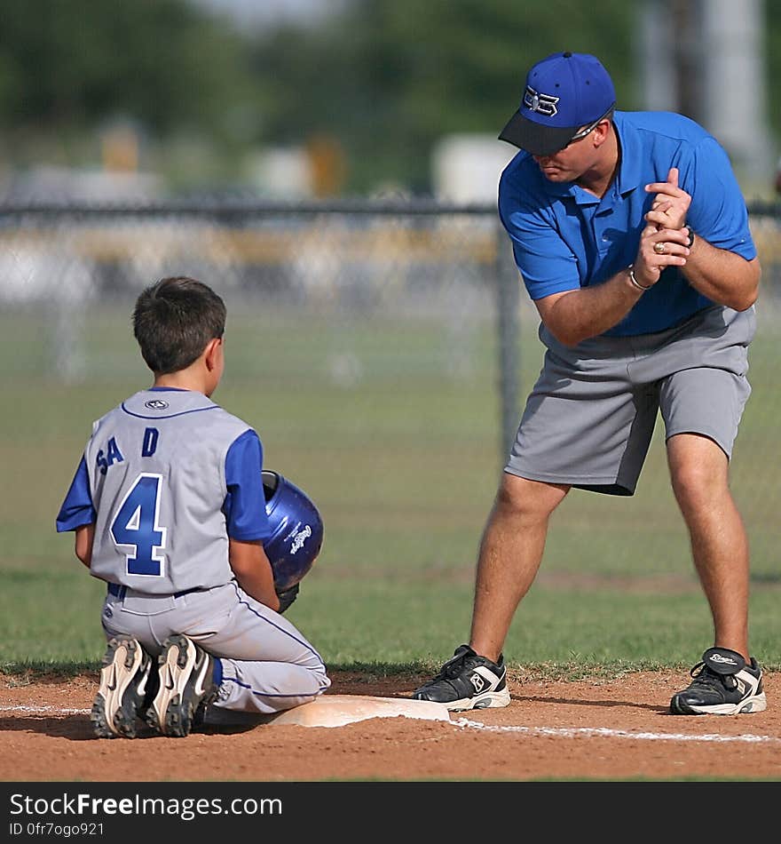 A baseball coach training a young player on the field.