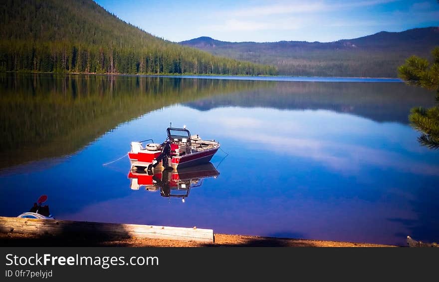 A blue lake with a boat in the still water. A blue lake with a boat in the still water.