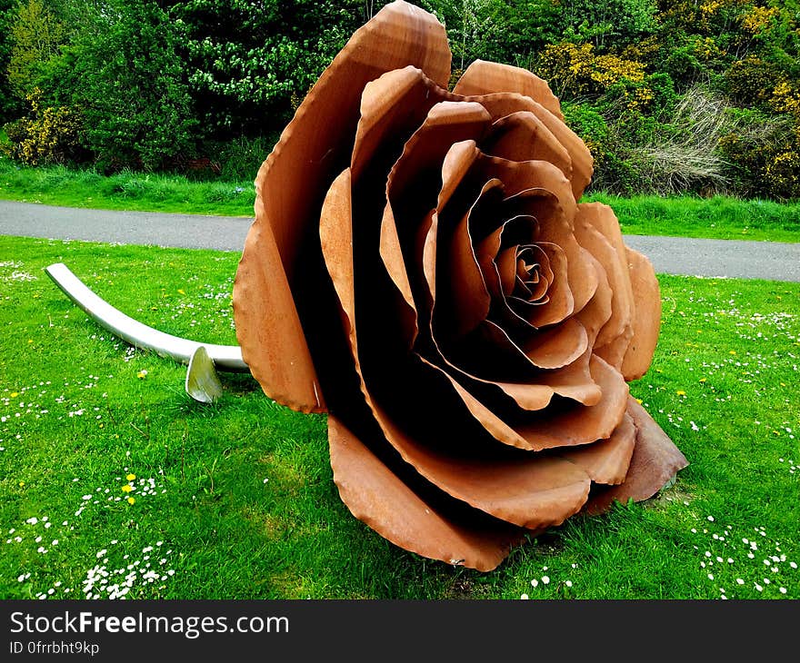 A sculpture of a rose in a park. A sculpture of a rose in a park.