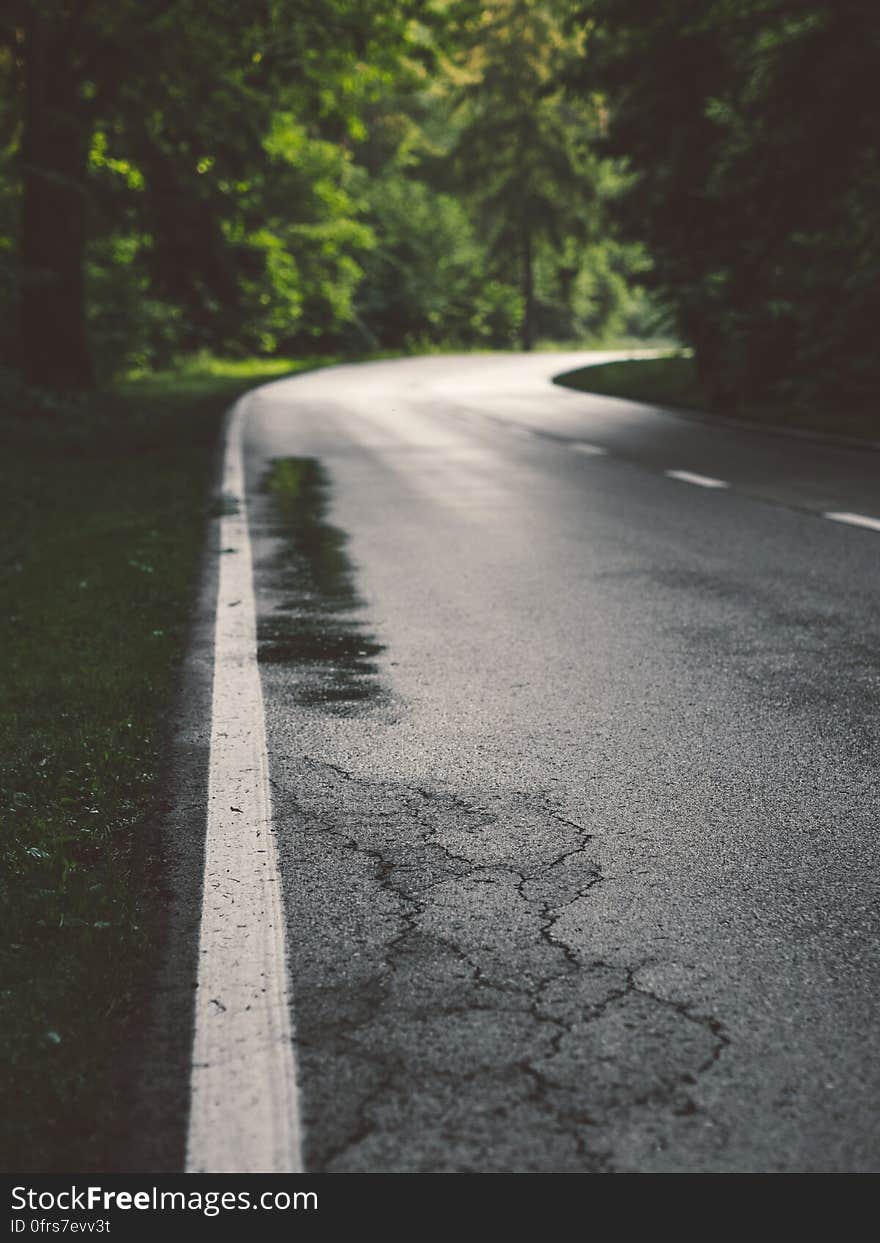 Low angle view of curving road in countryside with cracked asphalt.