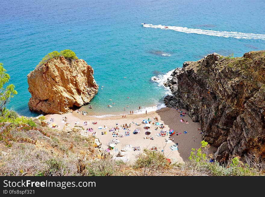 Small sandy beach with large rock beside an aquamarine sea with speedboat crossing the bay. Small sandy beach with large rock beside an aquamarine sea with speedboat crossing the bay.