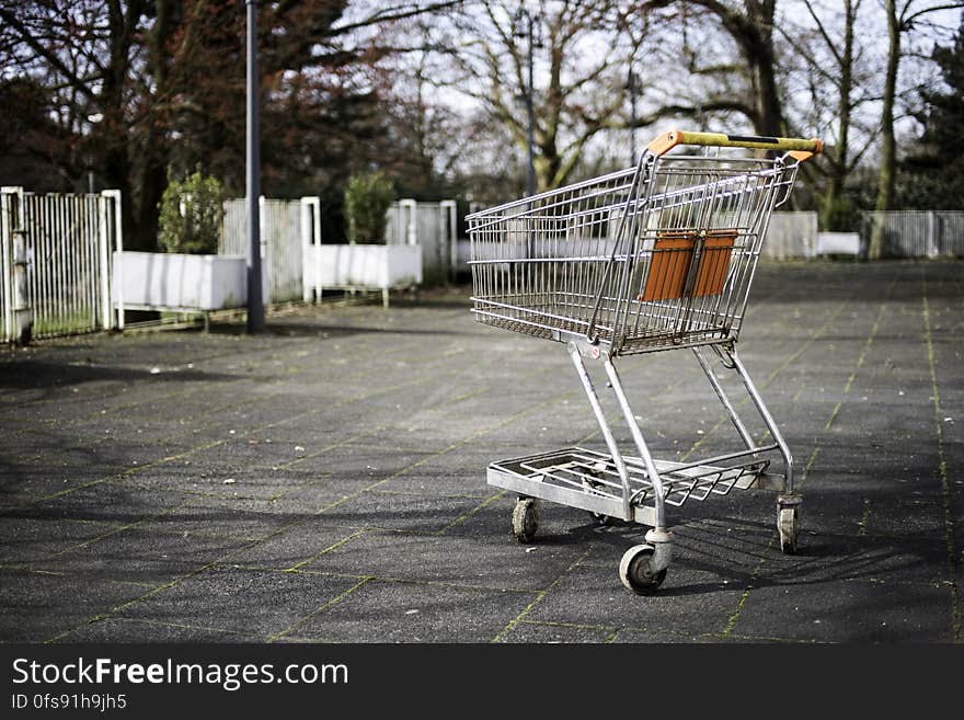 An empty shopping trolley on a pavement.