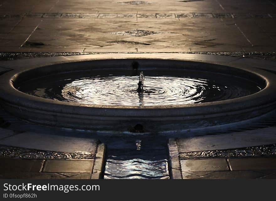 An outdoor fountain surrounded by a pool.