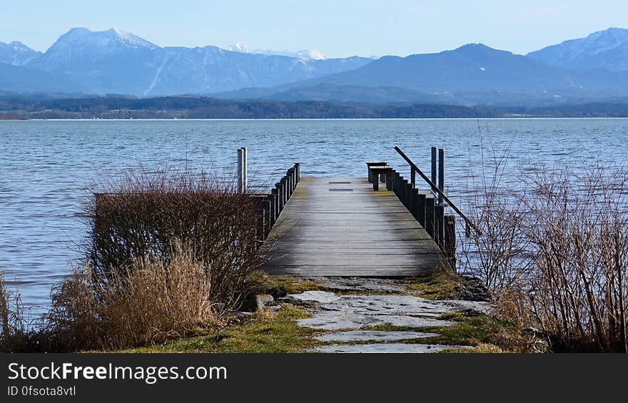 A pier leading off into the water with mountains in the horizon. A pier leading off into the water with mountains in the horizon.