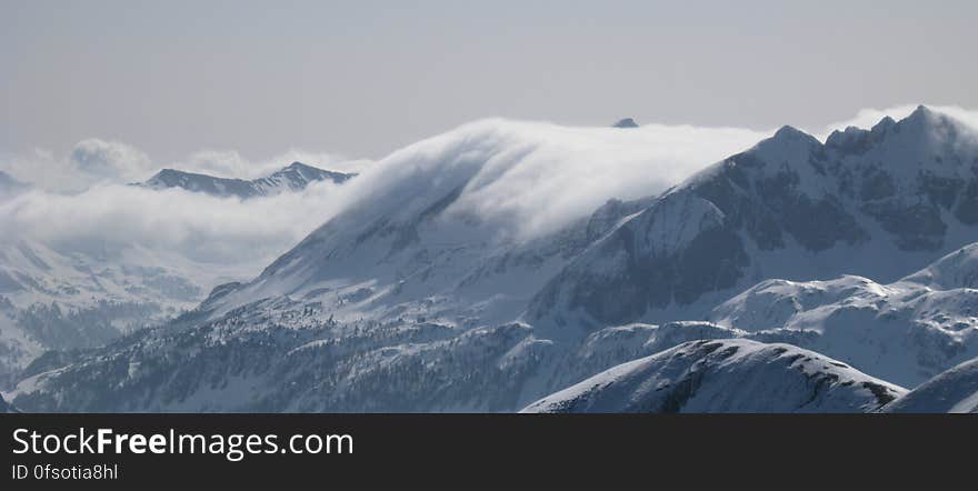 A snowy mountain range with clouds covering the peaks. A snowy mountain range with clouds covering the peaks.