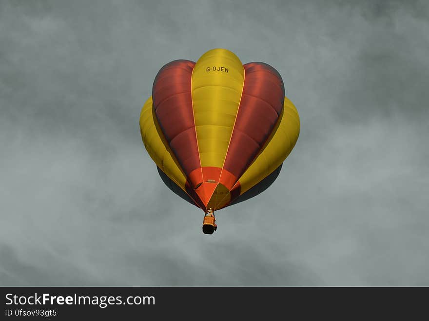 Red and Yellow Hot Air Balloon Under Sea of Clouds