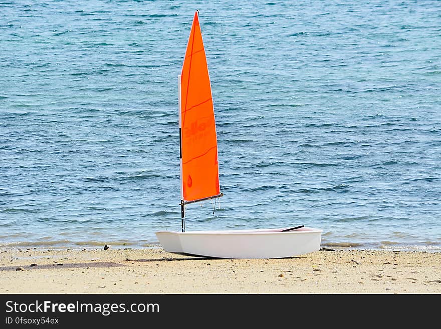 A single sail boat on sandy beach. A single sail boat on sandy beach.