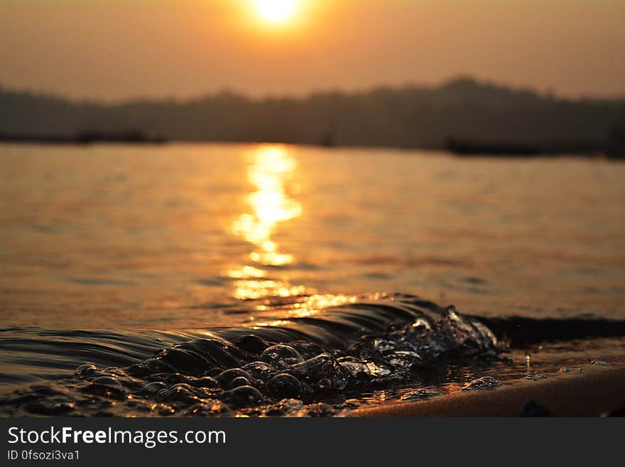 A sunset on a beach with waves hitting ashore. A sunset on a beach with waves hitting ashore.