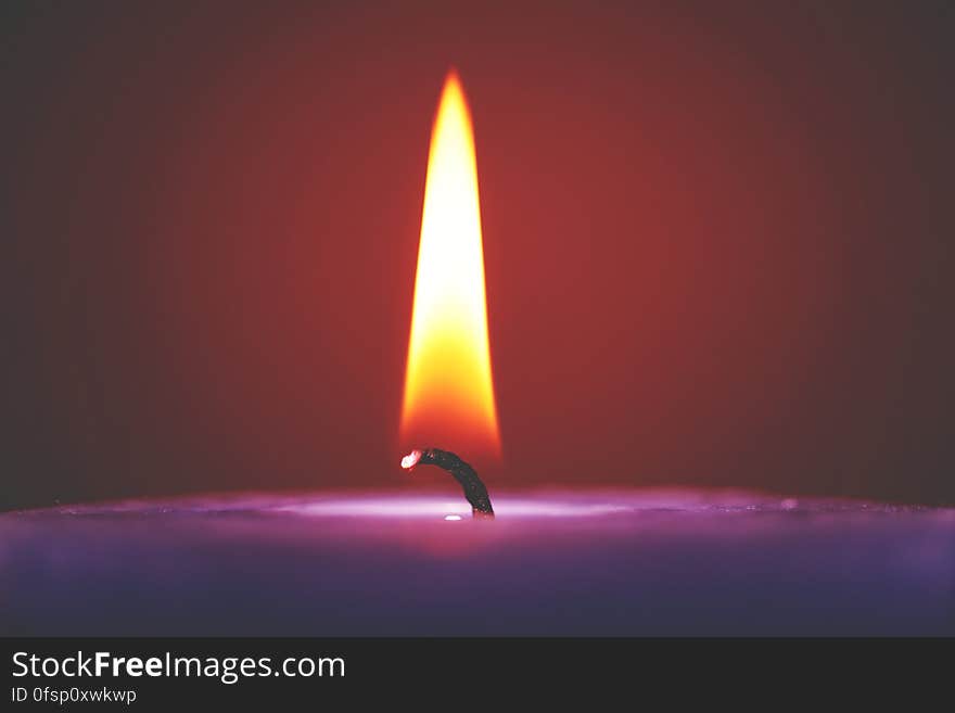 A close up of a burning violet candle. A close up of a burning violet candle.