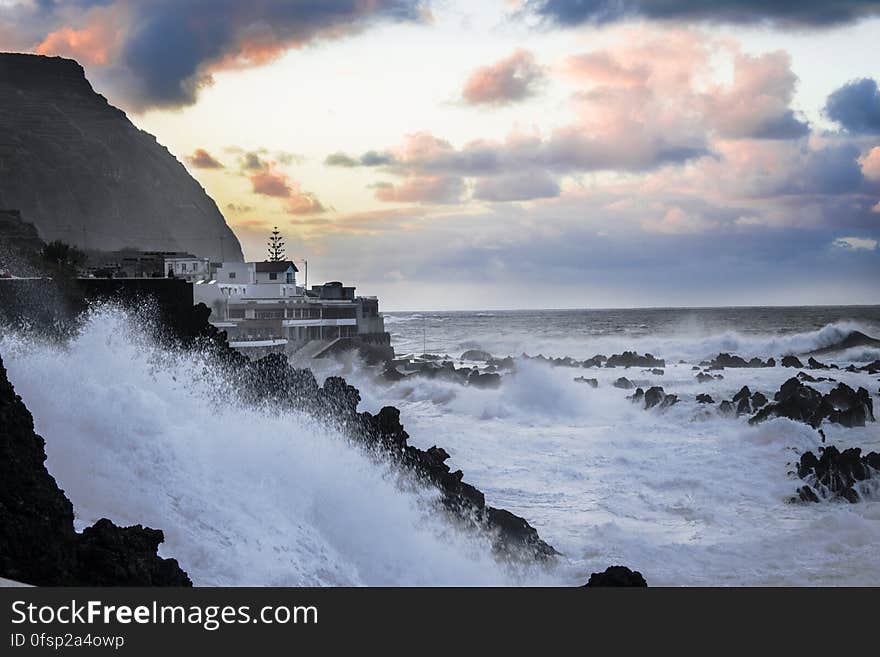 A view of a coast with houses and stormy weather with waves hitting the rocks. A view of a coast with houses and stormy weather with waves hitting the rocks.