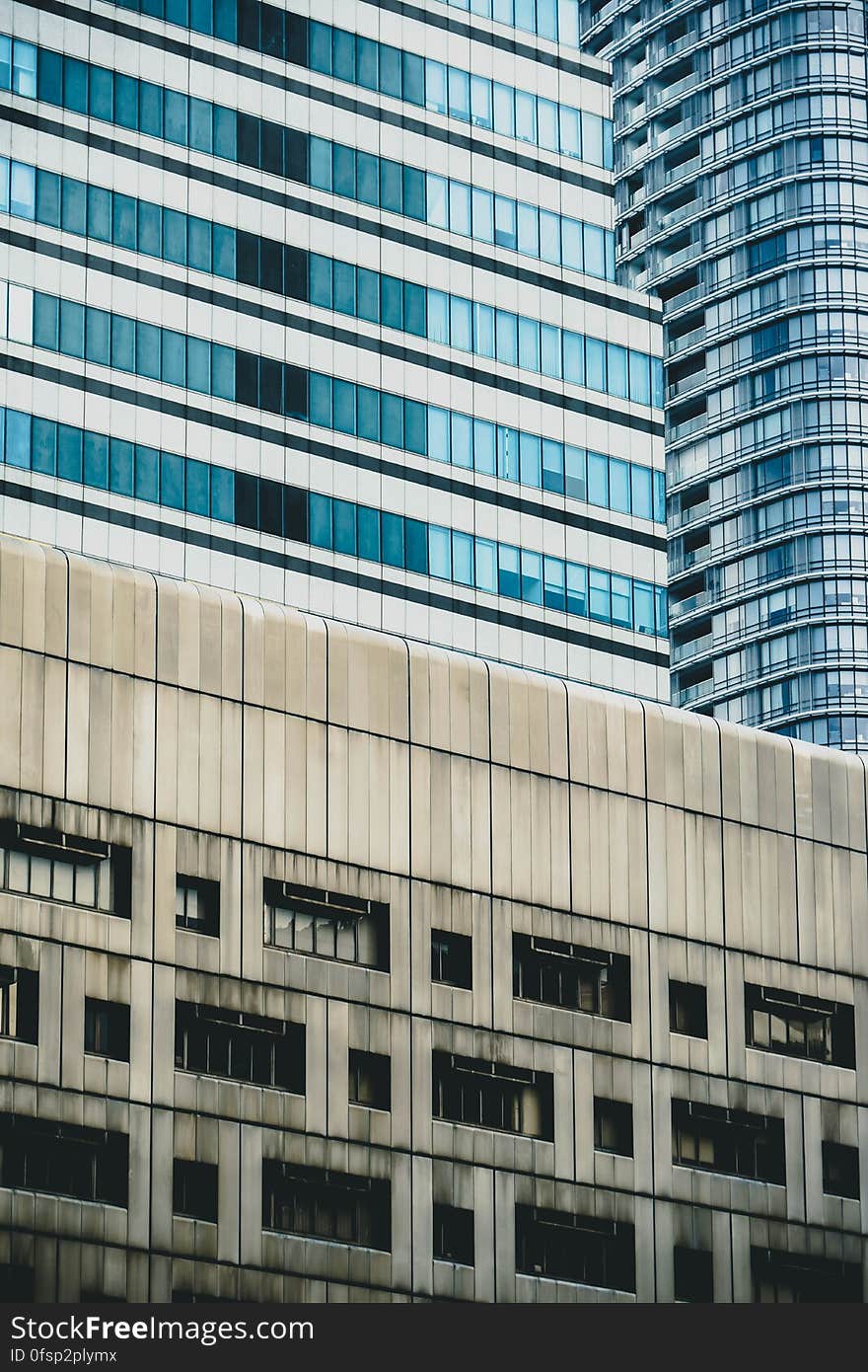 Urban architecture with concrete building and glass skyscrapers on the background.