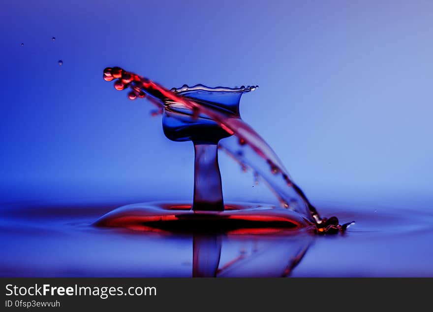 A close up of a water drop splashing on a water surface.