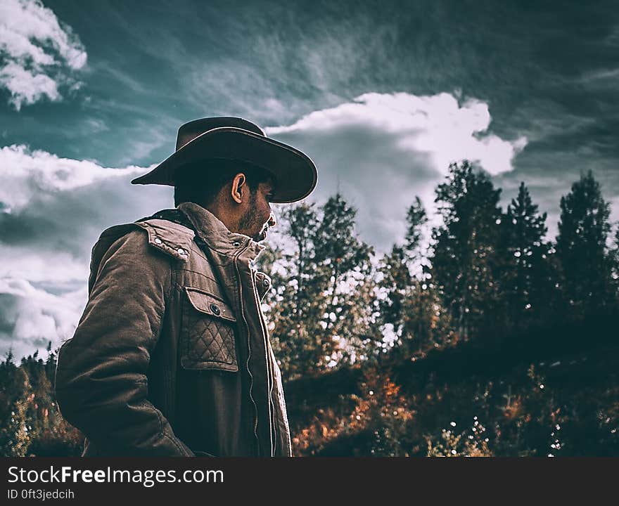 A man wearing a cowboy hat and jacket out on a field. A man wearing a cowboy hat and jacket out on a field.