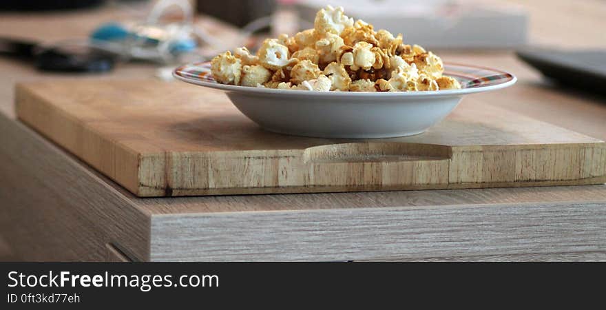 A bowl of popcorn on a plate on kitchen counter.