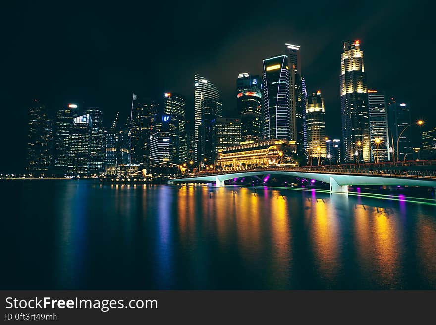 Singapore skyline illuminated at night reflecting in waterfront marina. Singapore skyline illuminated at night reflecting in waterfront marina.